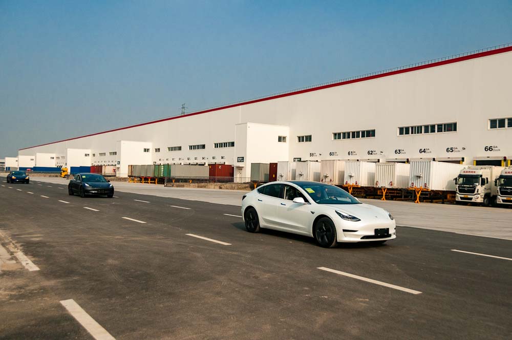 A row of Chinese made Tesla Model 3s driving past the new Tesla factory in Lingang, Shanghai.